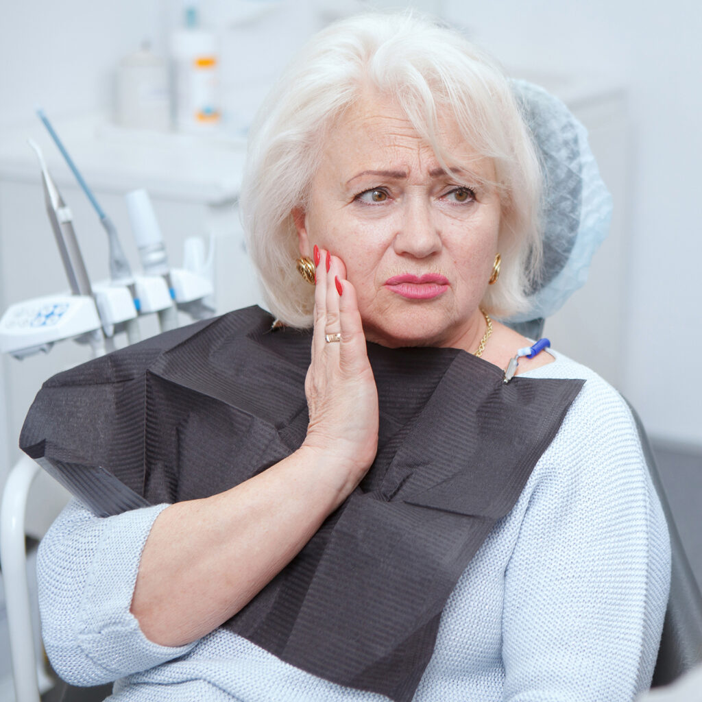 Elderly woman suffering from toothache, visiting dentist