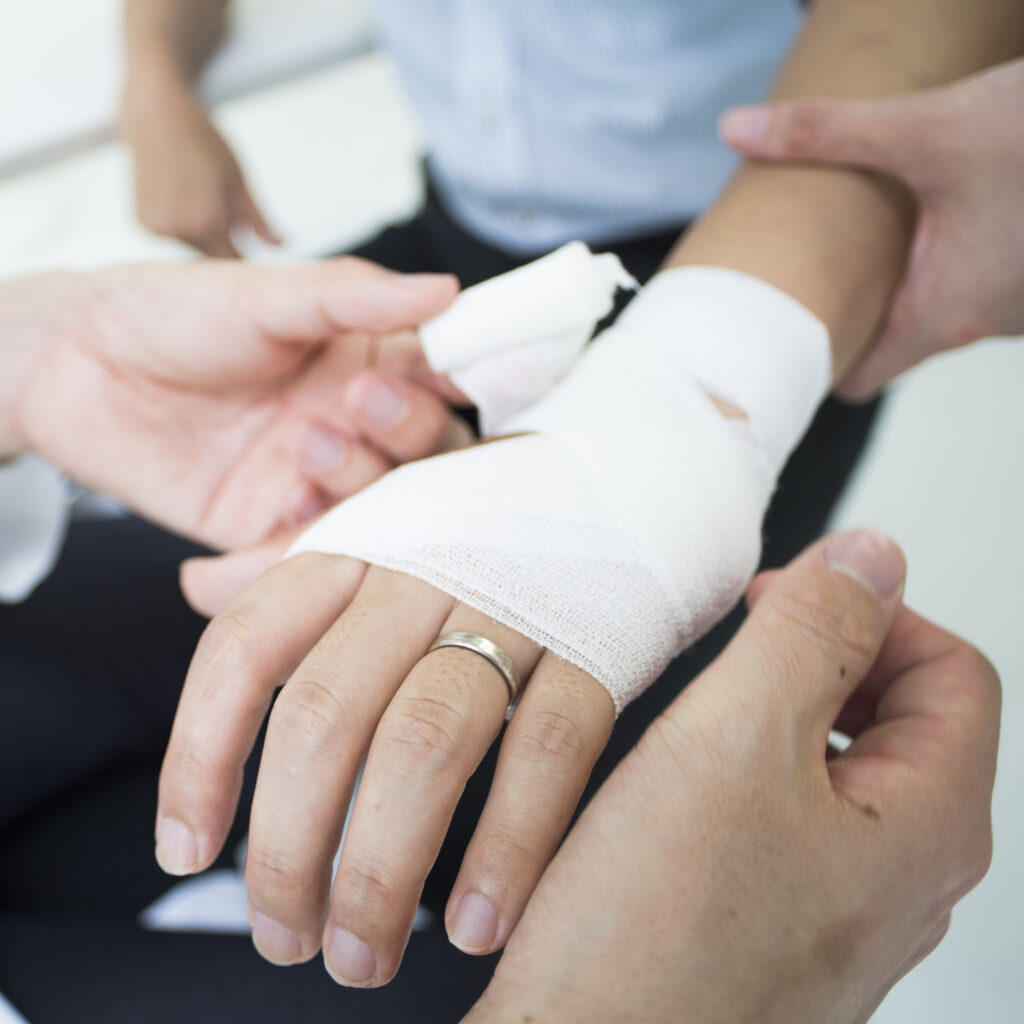 The doctor wraps a bandage on the arm of the injured patient.